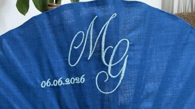 Détail du monogramme et de la date brodés en fil clair sur tissu bleu