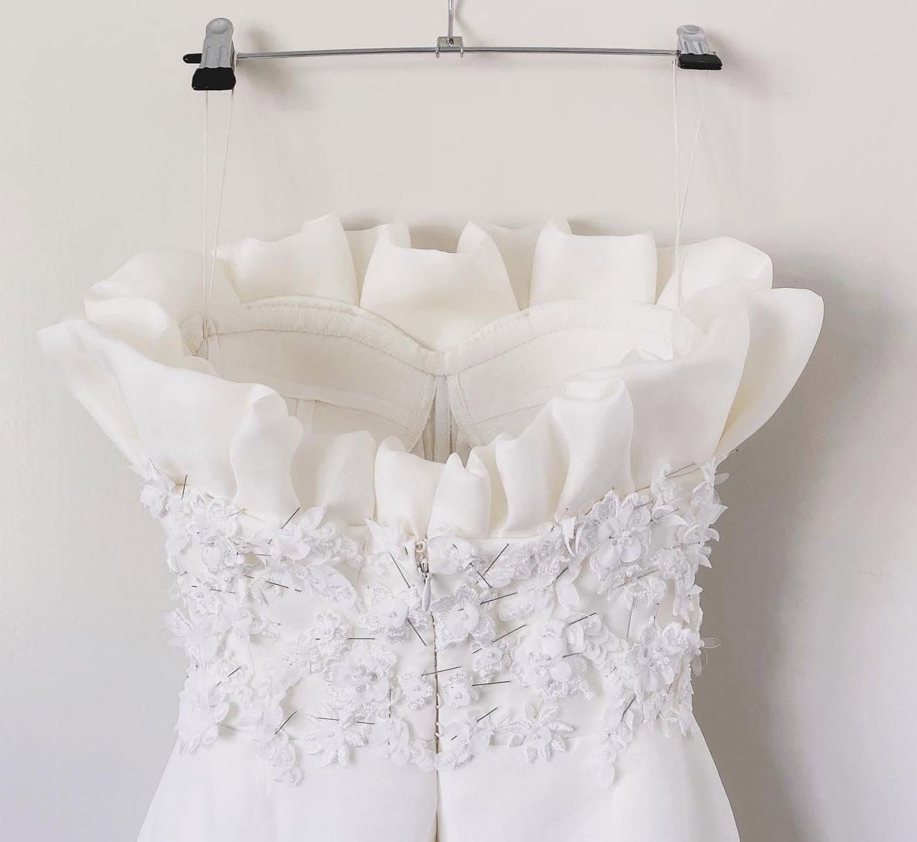 Détail d’une pièce ivoire en cours de confection, avec applications florales épinglées et superpositions de tissu