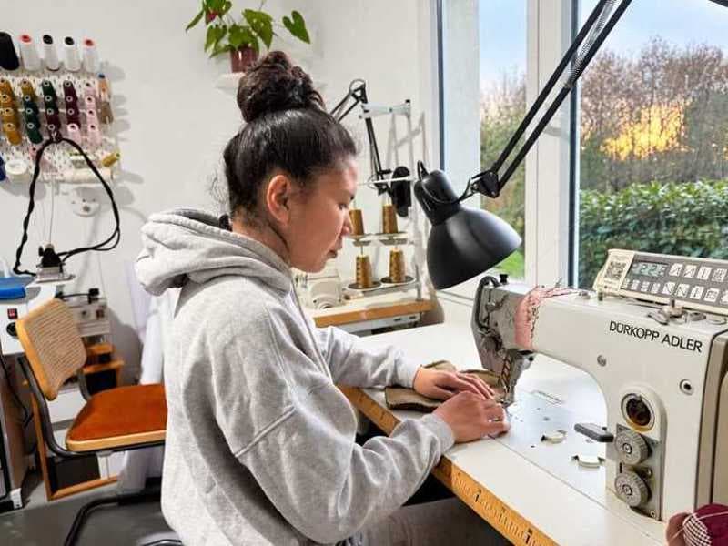Travail à la machine à coudre dans l’atelier en Bretagne, près de la fenêtre donnant sur le jardin