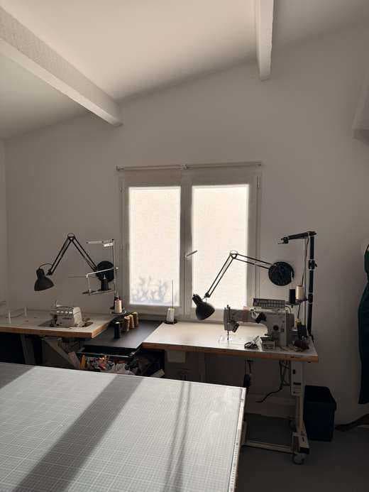 Machines industrielles de couture et surjeteuse devant la fenêtre de l’atelier