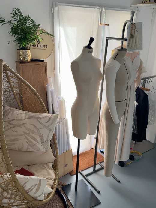 Salon du showroom avec fauteuil en rotin, mannequins et espace d’accueil